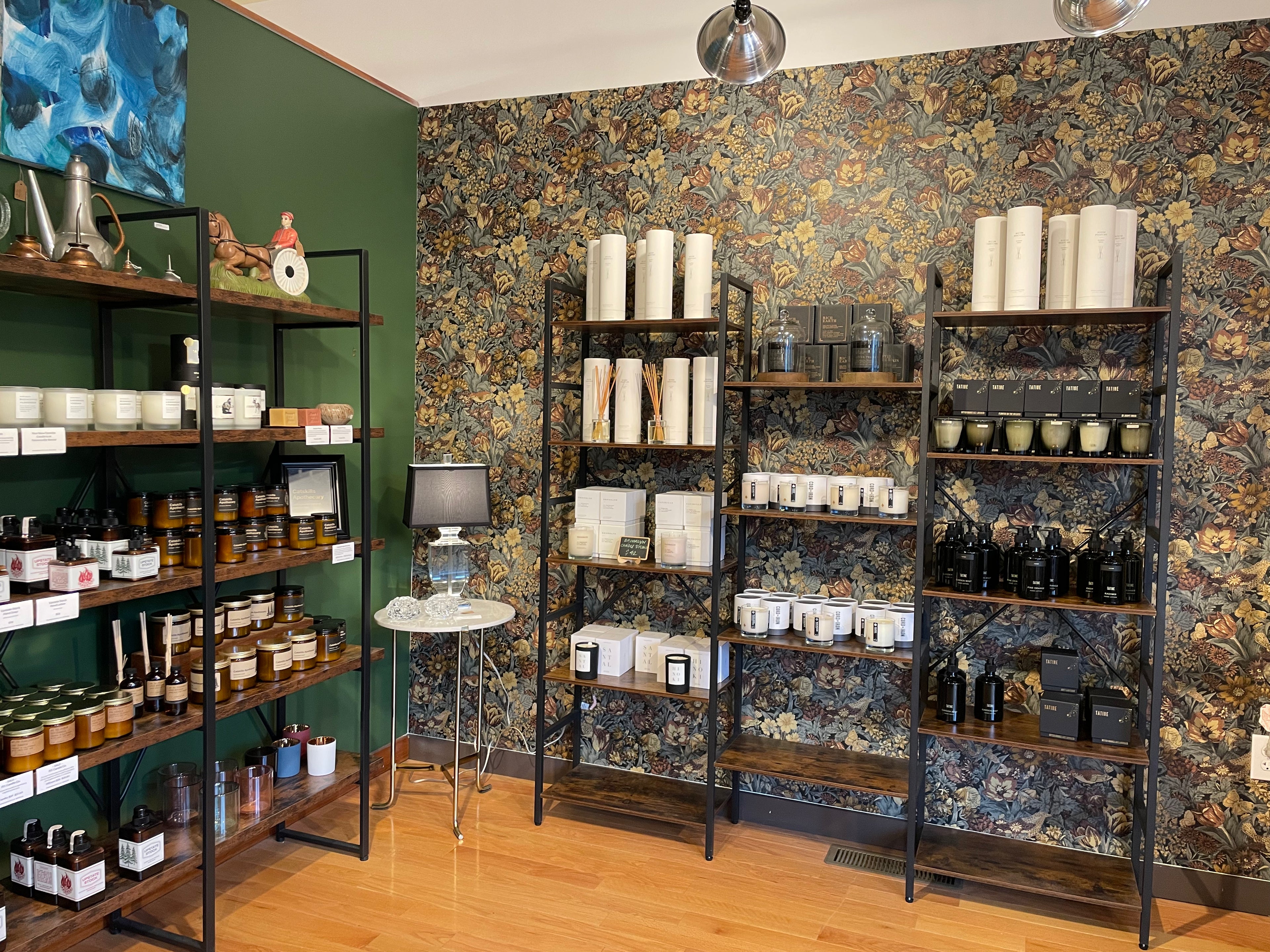 Shelves with various products in a store setting with patterned wallpaper.